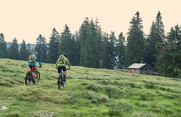 Radfahrer auf dem Weg über ein Feld zu einer Hütte im Bayerischen Wald.