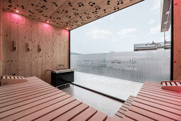Die modern gestaltete Sauna des Tonihof lädt mit einem großzügigen Fenster und beeindruckendem Ausblick zum Entspannen ein.